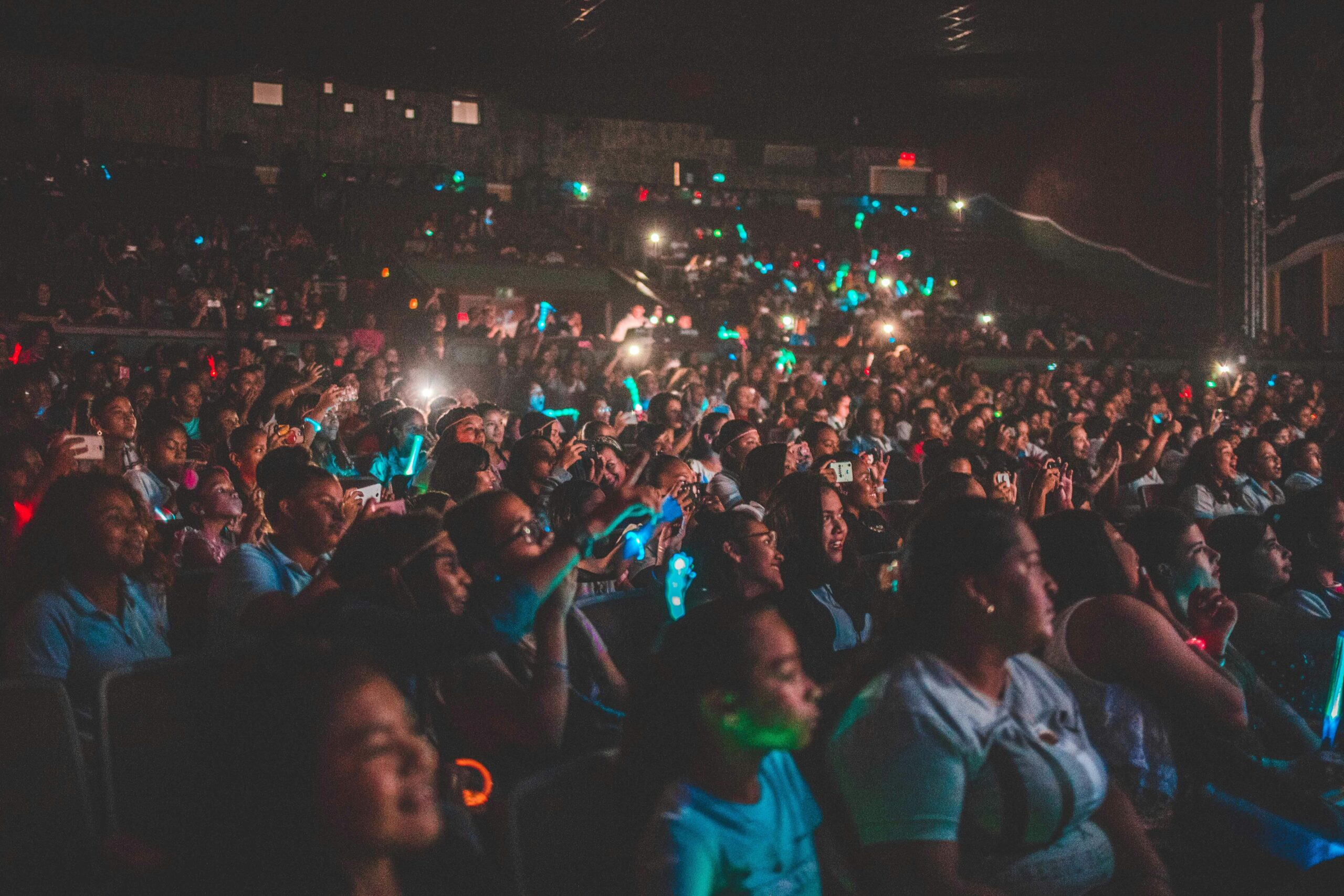 A vibrant audience enjoying a live music concert with colorful lights in a large venue.