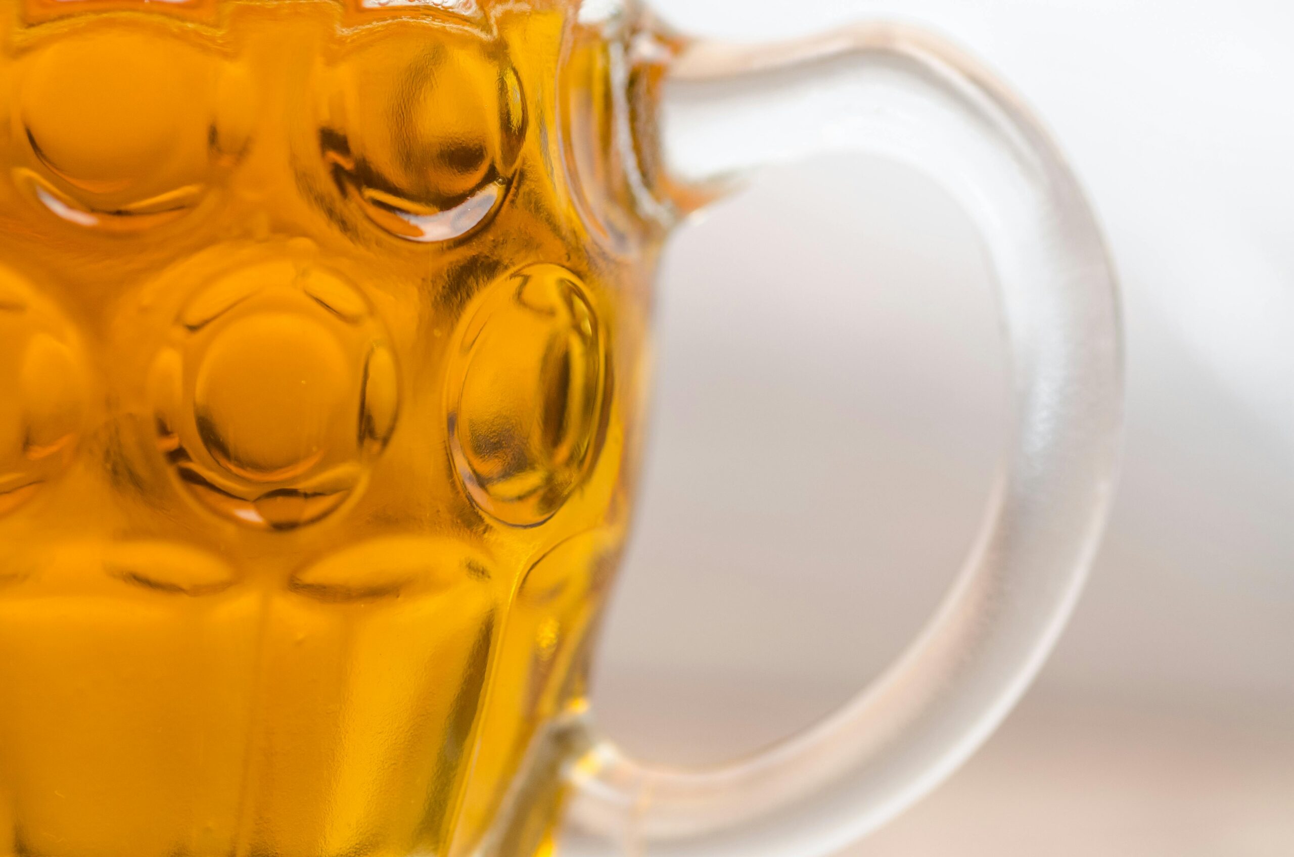A close-up view of amber beer in a textured glass mug, highlighting the refreshing beverage.